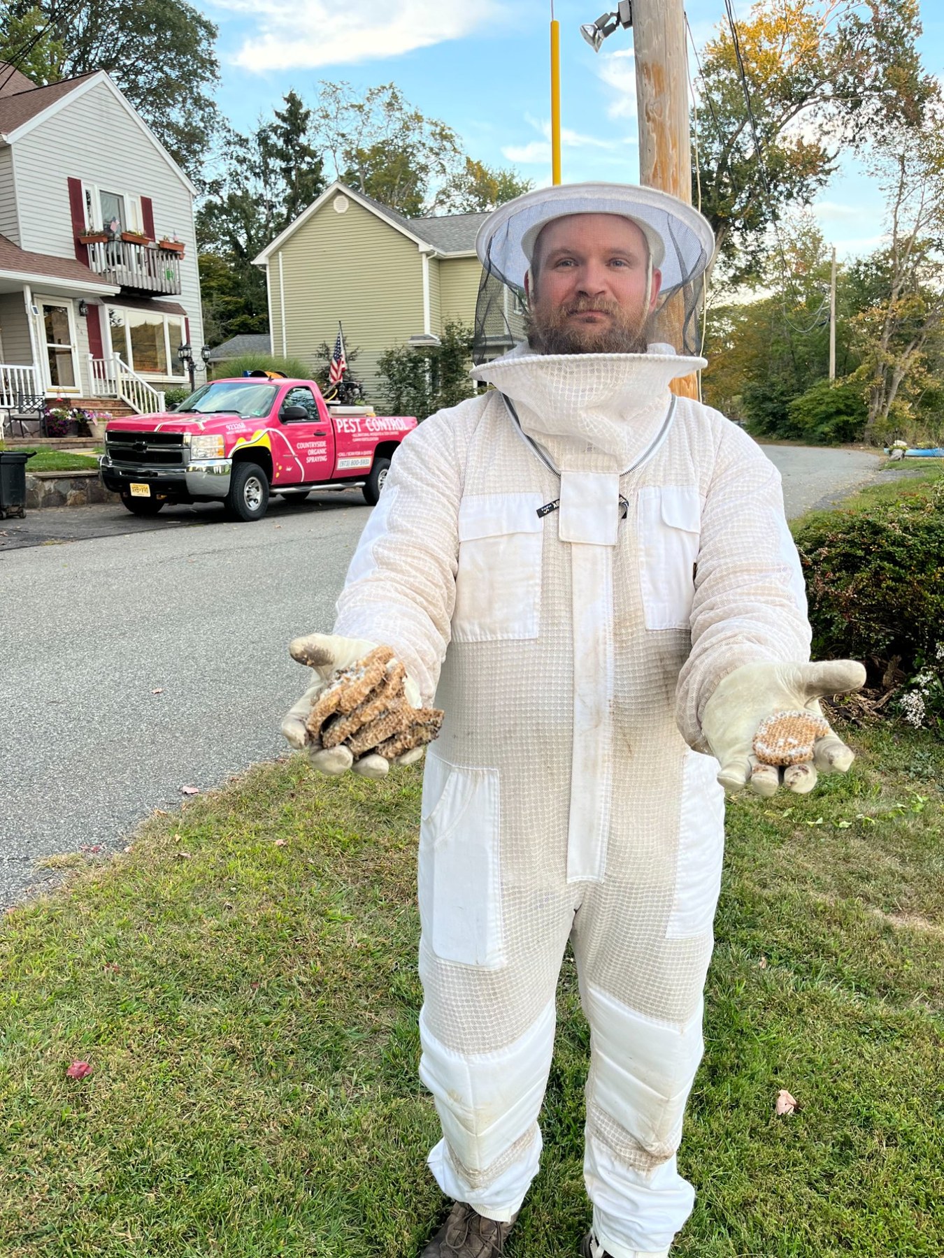 Joey in full bee suit after large bee hive removal, pink truck in background