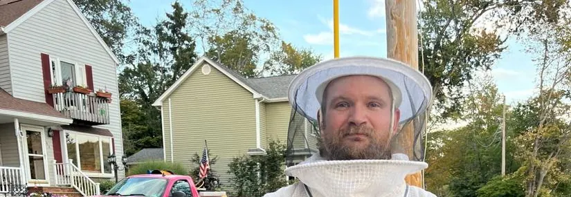 Joey in full bee suit after large bee hive removal, pink truck in background